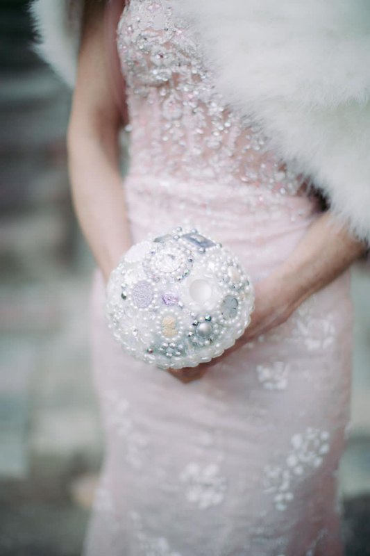 Sposa che stringe un bouquet gioiello Unusual Bouquet coordinato a un abito nuziale di alta moda.