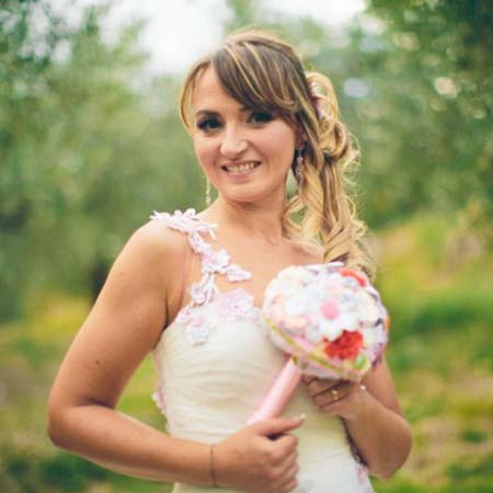 Sposa sorridente con mini bouquet da lancio economico in carta e materiali di riciclo