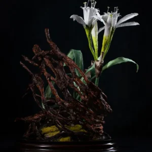 Composizione floreale scultorea con gigli di mare in seta e radici di carta riciclata su base di sabbia.
