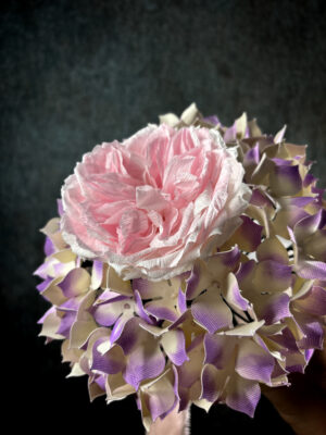 Primo piano ravvicinato dei petali realistici di una rosa inglese rosa in carta crespa pregiata all'interno di un bouquet da sposa.