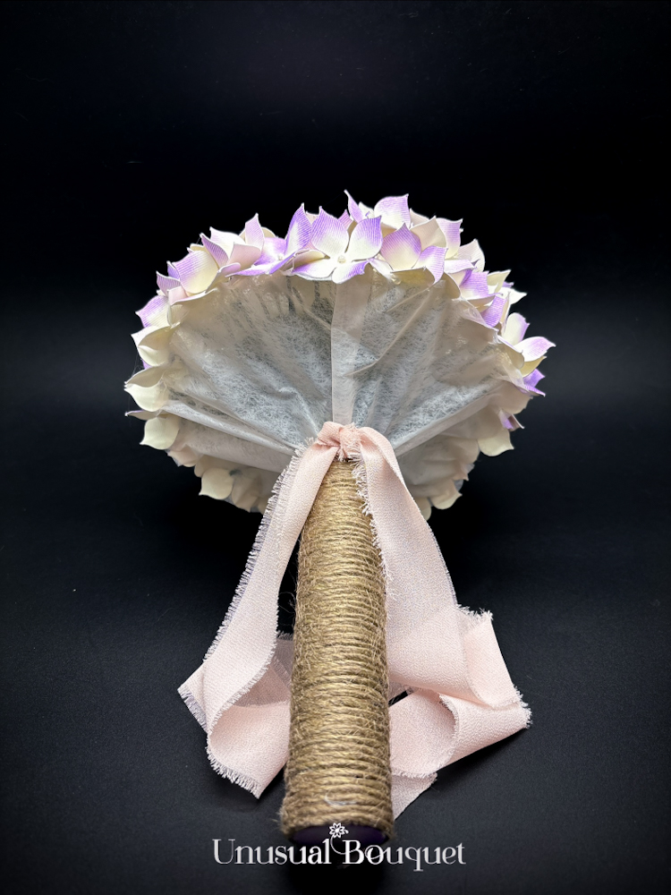 Particolare del sotto calotta e dell'attacco del manico in corda con fiocco di nastro sfrangiato, logo Unusual Bouquet in evidenza.